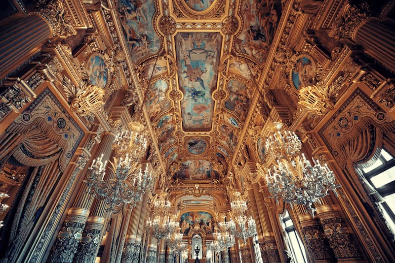 The opulent Grand Foyer of the Palais Garnier with its painted ceilings and chandeliers